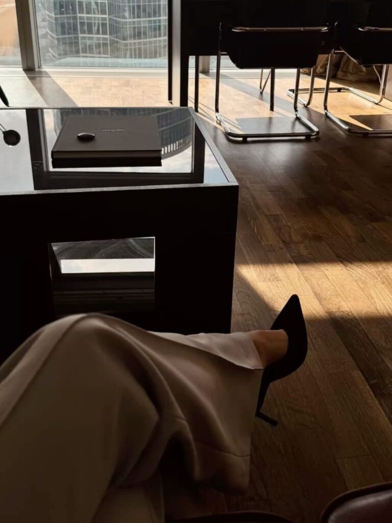 Preduzetnica u elegantnom poslovnom prostoru sa visokim potpeticama, simbol autoriteta i prisustva